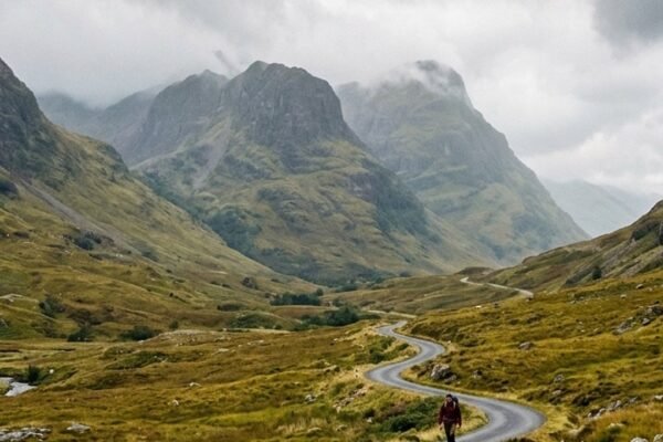 Solo female traveler looking out panoramic train window over dramatic Scottish Highlands scenery — scotland without a car